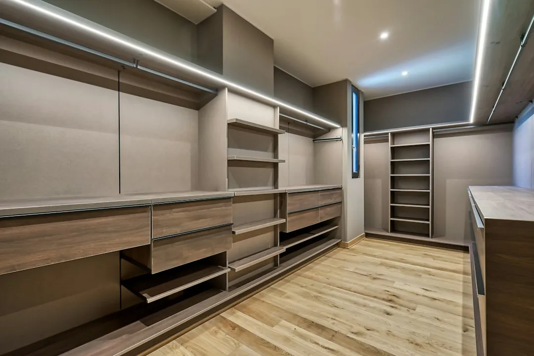 Dressing en pièce dédiée avec caissons à tiroirs en bois, penderies et éclairage LED intégré sous les tablettes