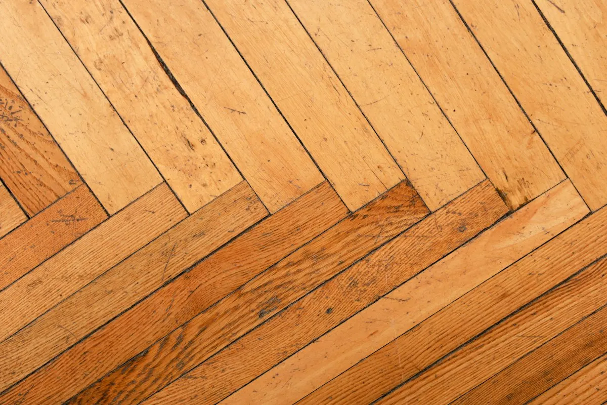 Parquet ancien en bâtons rompus, lames usées et marquées avant ponçage