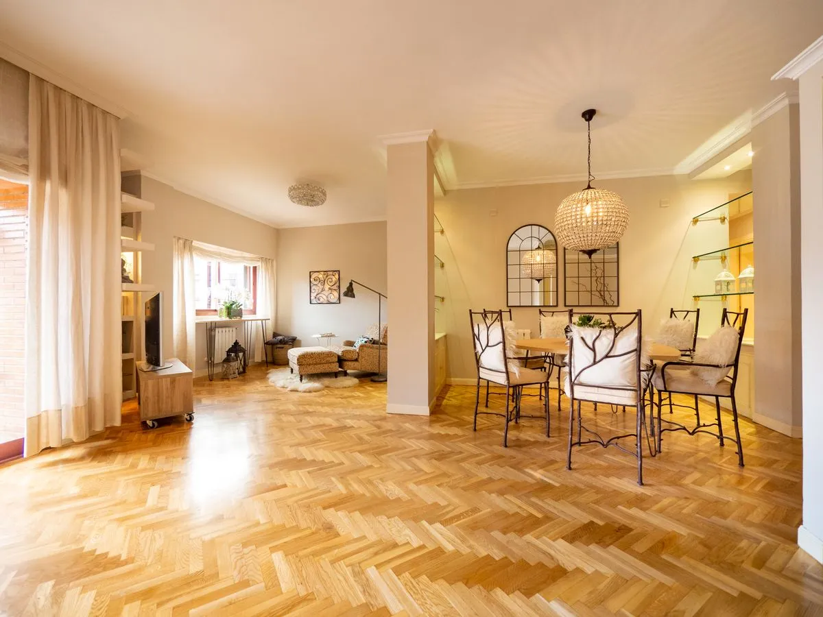 Séjour d'appartement ancien au parquet en chêne clair posé à bâtons rompus, avec coin salle à manger sous un lustre