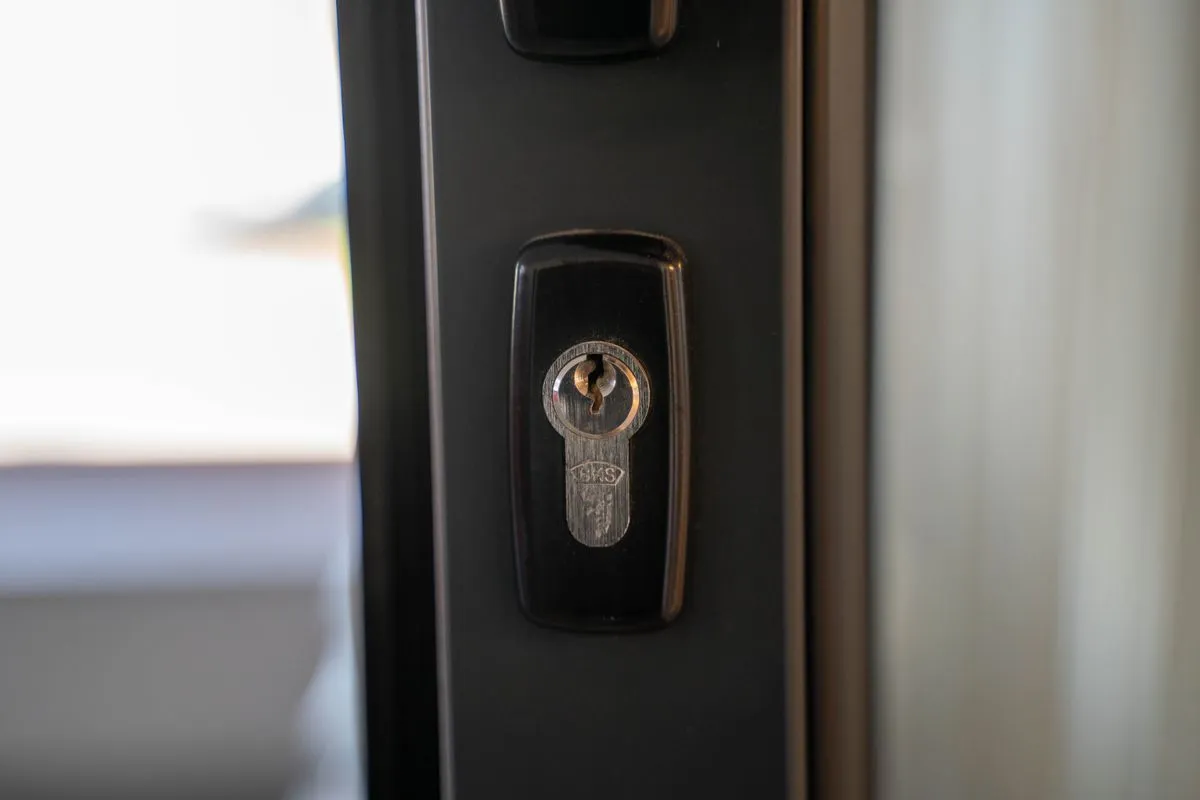 Cylindre de serrure en acier inoxydable dans une rosace noire sur le chant d'une porte d'entrée moderne