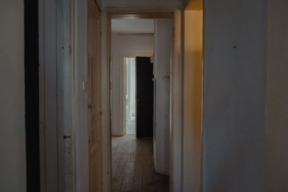 Couloir d'appartement ancien au parquet de bois brut, bordé de portes intérieures en enfilade
