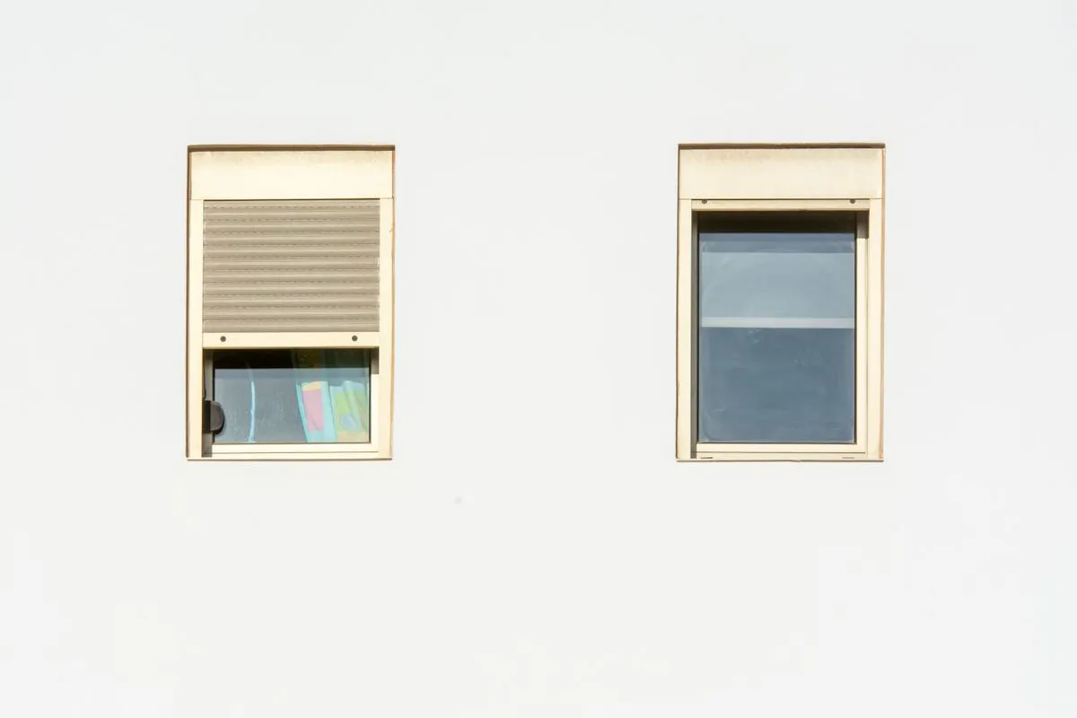 Façade blanche avec deux fenêtres à coffre de volet roulant en applique, l'un à mi-hauteur, l'autre relevé